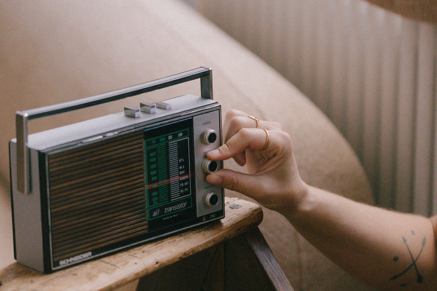 Une personne tourne le bouton d’une radio vintage, symbolisant l’ouverture à la médiumnité d’évidence et l’écoute des signes et intuitions invisibles